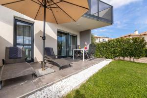 een terras met een tafel, stoelen en een parasol bij Apartment Elegance in Krk