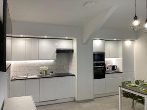a kitchen with white cabinets and a dining room at Appartement Altea 85 m2 climatisé parking proche Sanctuaires in Lourdes