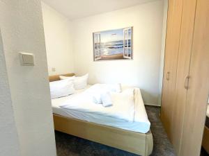 a bedroom with a bed with white sheets and pillows at Apartmenthaus Frauenpreiss FeWo 303 in Cuxhaven +9 photos