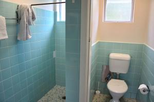 baño con aseo y azulejos azules en Wards Holiday Flat 2, en South West Rocks