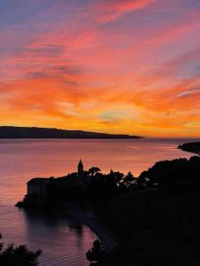 a sunset over a body of water with a building at House Smokovlje in Bol