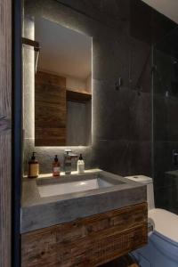 a bathroom with a sink and a toilet and a mirror at Espectacular casa con hermosa vista al lago - El Santuario Resort in Colorines