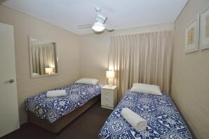 ein Schlafzimmer mit zwei Betten und einem Spiegel in der Unterkunft Riverview Holiday Apartment 11 - Kalbarri, WA in Kalbarri + 9 Fotos