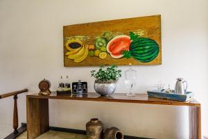 a table with a painting of fruit on the wall at Pousada Encanto de Tiradentes in Tiradentes