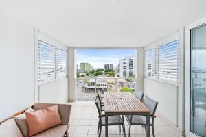 a living room with a table and chairs and a balcony at Belle Escapes 710 Elevated CBD getaway with magical views in Cairns