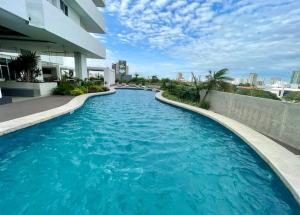 ein Swimmingpool vor einem Gebäude mit blauem Wasser in der Unterkunft Apartamento Lujoso y Comodo con la mejor vista panoramica de Santa Cruz in Hamacas
