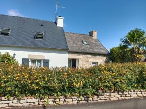 a white house with a stone wall and flowers at gite du guip in Trégourez