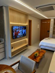 ein Hotelzimmer mit einem Bett und einem Flachbildfernseher in der Unterkunft Flat Amura Carneiros in Praia dos Carneiros