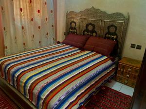 - une chambre avec un lit et une couette colorée à rayures dans l'établissement Riad Nezha avec jacuzzi et au cœur de Marrakesh, à Marrakech