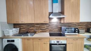 ロマンヴィルにあるL'Écrin Parisien - Proche Métro -Direct Paris - 4 personnesのキッチン(木製キャビネット、シンク、電子レンジ付)