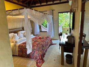 a bedroom with a bed with a canopy at Pousada Enseada do Espelho in Praia do Espelho