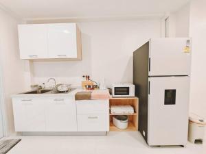 a white kitchen with a refrigerator and a sink at Baan-B BangSaen in Ban Bang Saen (1)
