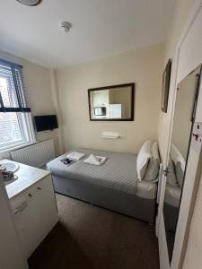 a small room with a bed and a mirror at Winston House Guesthouse in Bridlington