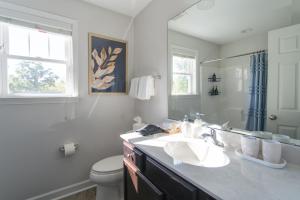 a bathroom with a sink and a toilet and a mirror at Fam-Biz Friendly 3BD with Fire pit & BBQ - Downtown in Raleigh +44 photos