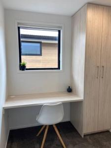 a desk with a white chair and a window at Modern, trendy apartment in Lower Hutt