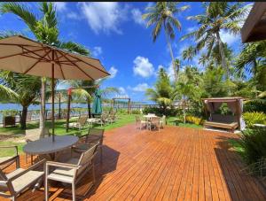 eine Terrasse mit Tisch und Stühlen und einem Sonnenschirm in der Unterkunft Flat Amura Carneiros in Praia dos Carneiros