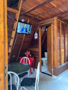 a room with a table and a tv in a cabin at Chalés Lemes in Anchieta