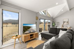 a living room with a couch and a large window at Sandy Toes by Experience Jervis Bay in Vincentia