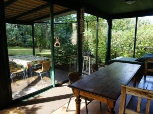 eine abgeschirmte Veranda mit einem Holztisch und Stühlen in der Unterkunft Villa Mimosa Comfortable holiday residence in Lacanau