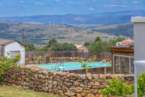 una piscina con un muro di pietra e una recinzione in pietra di Casa CORTIJO Piscina privada a Tarifa