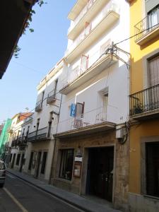 un grand bâtiment blanc avec balcon dans une rue dans l'établissement Hotel del Mar, à Sant Feliu de Guíxols