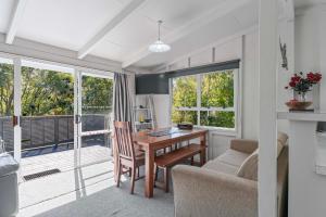 a living room with a table and chairs and windows at Duck Inn - Lake Taupo Holiday Home in Turangi