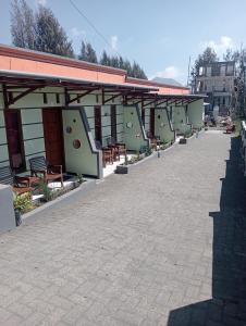 a patio of a building with benches and tables at Mentigen Homestay in Ngadisari