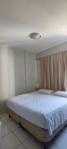 a bedroom with a large bed with white sheets at Golden Dolphin Supreme in Caldas Novas