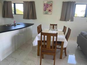 a dining room with a table and chairs and a kitchen at Eryns Retreat in Avarua