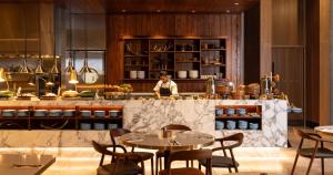 a chef in a kitchen with tables and chairs at Horizon by SkyCity in Auckland