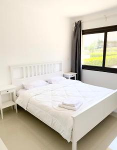 a white bedroom with a white bed and a window at El Gouna -G-cribs B6 in El Gouna