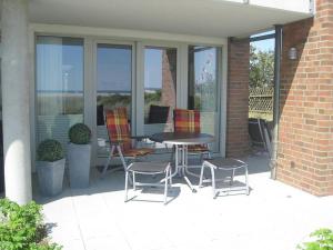 a patio with a table and chairs and windows at Poseidon in the Amrumer Welle in Wittdün