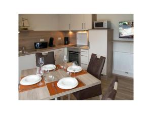 a kitchen with a table with plates and wine glasses at Holiday apartment Balkenstek in Norddeich +7 photos