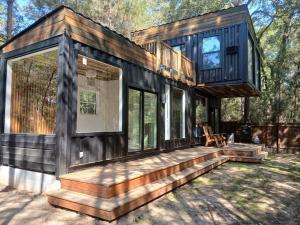 a large wooden house with a porch and stairs at Waterfront Container House In A Magical Forest! in Waller