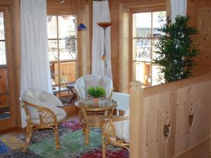 Una sala de estar con sillas y una mesa y ventanas. en Hintermair Comfortable holiday residence, en Garmisch