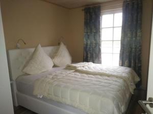 a bedroom with a bed with pillows and a window at Klabautermann Comfortable Holiday Residence in Greetsiel