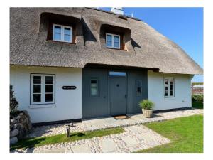 a thatch roofed house with a blue garage at Oceans 18 Comfortable holiday residence in Wenningstedt