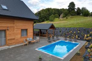a patio with a pool and chairs and a house at Holiday Home Wi niowa with Pool and Mountain Views in Iwierzyce