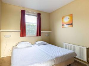 a bedroom with a large white bed with a window at Wilgenroos Vakantiepark De Groote Vliet in Wervershoof
