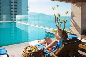 a person laying in a chair next to a pool at Gonsala Hotel Nha Trang in Nha Trang