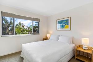 una camera da letto bianca con un letto grande e una finestra di Oceanfront 3-Bed Retreat with Pool-Steps to Beach a Caloundra