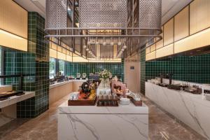 um restaurante com paredes de azulejos verdes e uma mesa longa em Atour Hotel Wuxi Huishan High-Speed Railway Station em Wuxi