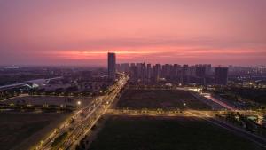 um horizonte da cidade à noite com muito tráfego em Atour Hotel Wuxi Huishan High-Speed Railway Station em Wuxi mais 4 fotografias