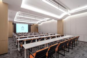 uma sala de aula vazia com mesas, cadeiras e uma tela em Atour Hotel Wuxi Huishan High-Speed Railway Station em Wuxi