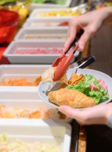 a person holding a plate with a sandwich and salad at RIHGA PLACE HIGOBASHI in Osaka