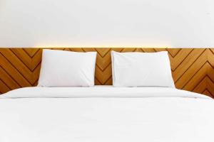 a bed with white pillows and a wooden headboard at Fancy and Elegant Studio at Patraland Urbano Apartment By Travelio in Bekasi +9 photos