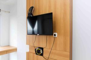 a flat screen tv mounted on a wooden wall at Fancy and Elegant Studio at Patraland Urbano Apartment By Travelio in Bekasi