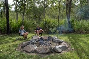 two people sitting in chairs around a fire pit at Airlie Beach Eco Cabins - Adults Only in Airlie Beach