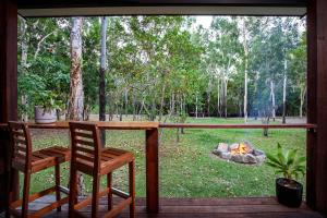 a porch with a table and two chairs and a campfire at Airlie Beach Eco Cabins - Adults Only in Airlie Beach