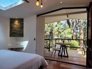 Un dormitorio con una cama y una mesa en una terraza. en Cabaña Aventurina- La pascana Ecolodge Entorno natural excepcional, conexión con la naturaleza y avistamiento de aves, Ubicado a 3km del metrocable y Parque Arvi, Guarne, en Mazo
